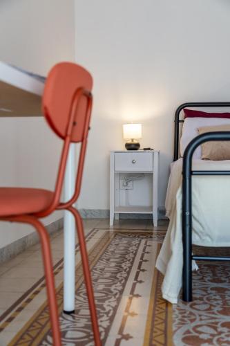 a red chair in a room with a bed and a table at La casa di Nina in Monte di Procida