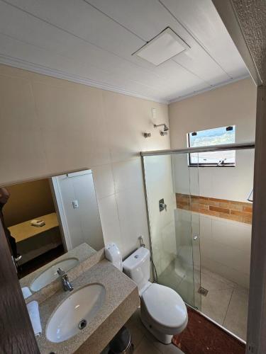 a bathroom with a toilet and a sink and a shower at Pousada Villa Serrana in Bom Jardim da Serra