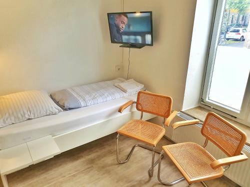 a room with a bed with two chairs and a tv at Aparthotel B & L in Bremen