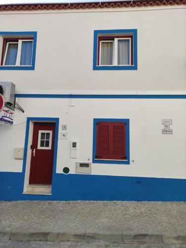 a blue and white building with red doors and windows at Casa de porto covo 2 in Porto Covo