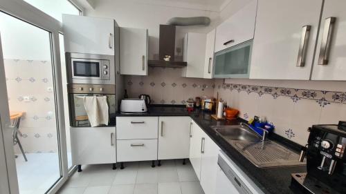 eine Küche mit weißen Schränken und einer Spüle in der Unterkunft Casa de porto covo 2 in Porto Covo