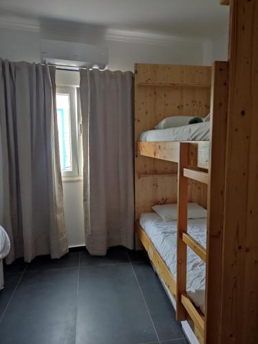 two bunk beds in a room with a window at Casa de porto covo 2 in Porto Covo