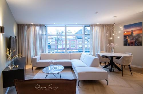 a living room with a white couch and a table at ApartHotel Boutique by Urban Home Stay in Alkmaar