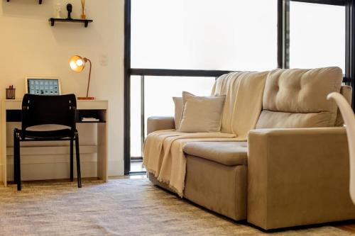 a living room with a couch and a desk and a chair at Studio moderno com garagem no kobrasol in São José