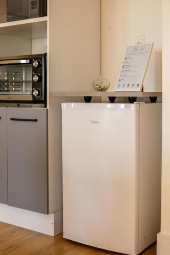 a white refrigerator in a kitchen next to a microwave at Studio moderno com garagem no kobrasol in São José