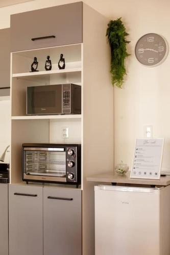 a kitchen with a microwave and a refrigerator at Studio moderno com garagem no kobrasol in São José