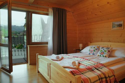 a bedroom with a bed in a room with a balcony at Domki JAWOR in Zakopane