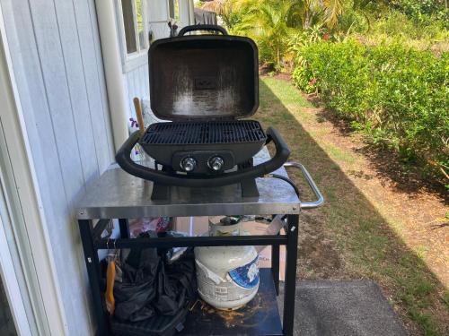a grill sitting on a cart outside a house at Comfort Nest in Pahoa