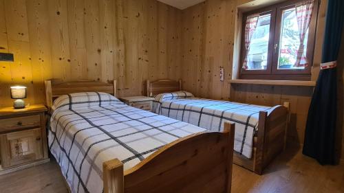 two beds in a room with wooden walls at Chez Ferdinand in Valtournenche
