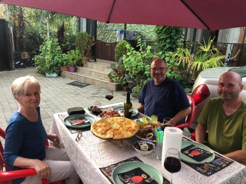 a group of people sitting at a table with a pizza at PAPILLON in Chakvi