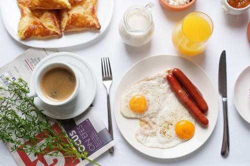 einen Tisch mit Frühstücksteller und einer Tasse Kaffee in der Unterkunft Eleven Inn Apartments Tbilisi in Tbilisi City