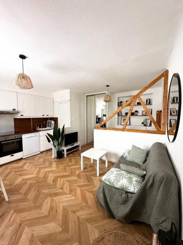un salon avec un canapé et une cuisine dans l'établissement Appartement cosy jardin et clim, à Sète