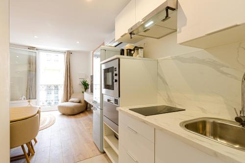 une cuisine blanche avec un évier et un micro-ondes dans l'établissement Très jolie deux chambres Neuf Climatisé - Centre ville historique, à Montpellier