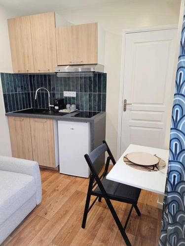 une cuisine avec une table et une chaise dans une pièce dans l'établissement Studio Moderne et confortable au coeur de Cambrai, à Cambrai