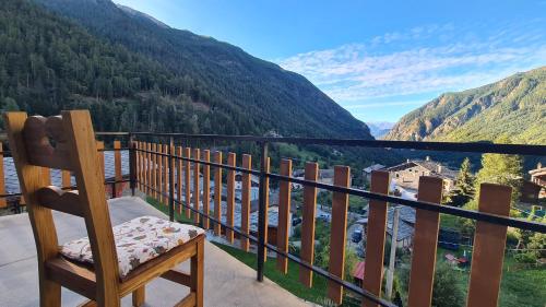 a wooden chair sitting on a balcony overlooking a valley at Chez Ferdinand in Valtournenche