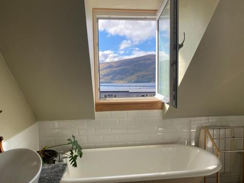 a bathroom with a bath tub and a window at Highland Rooms - Room Only No Breakfast in Ullapool