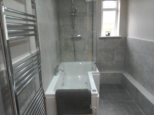 a bathroom with a bath tub and a window at The Dorchester Serviced Apartments in Hull