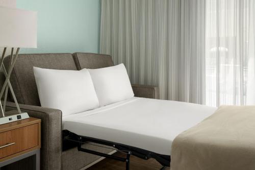 a bedroom with a bed and a couch and a window at Courtyard by Marriott Nassau Downtown/Junkanoo Beach in Nassau