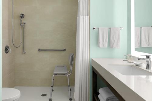 a bathroom with a shower and a chair in it at Courtyard by Marriott Nassau Downtown/Junkanoo Beach in Nassau