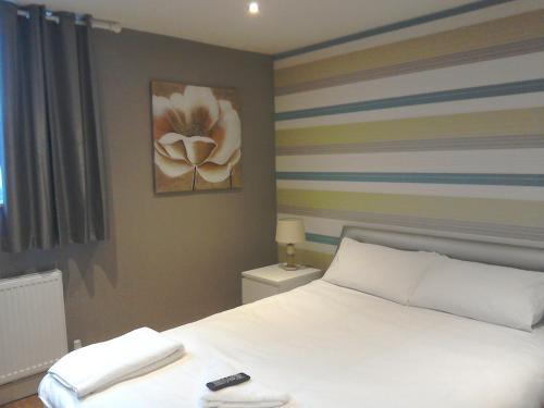 a bedroom with a white bed and a painting on the wall at The Dorchester Serviced Apartments in Hull