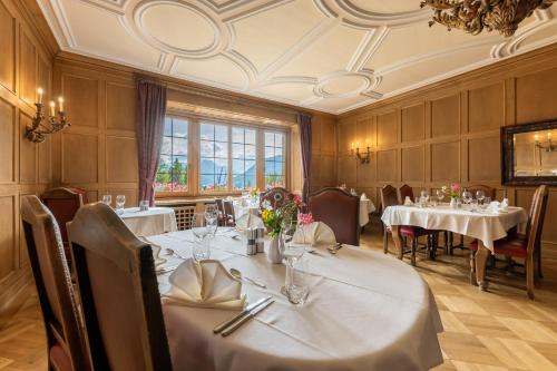 a dining room with tables and chairs and a chandelier at Hotel Chesa Spuondas in St. Moritz
