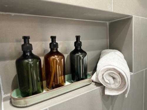 アテネにあるEstia Athens Apartmentの浴室の棚にタオルと一緒に3本のボトル
