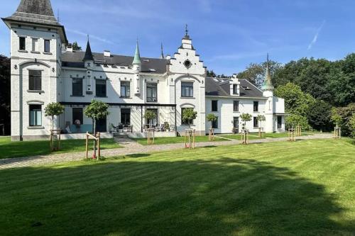 a large white house with a large grass yard at Vakantiewoning de Toren in Kortessem
