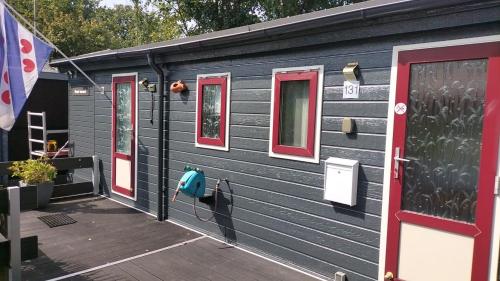 a black house with red windows and a deck at Groot hoek Chalet met Airco ,Wasmachine, Vaatwasser,Droger en luxe keuken en zwembad op camping! Immer Besser! in Rijs