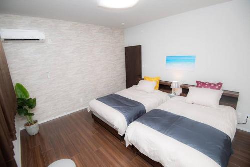 a bedroom with two beds and a potted plant at umikaze 2024年10月Open 新築物件 in Uruma