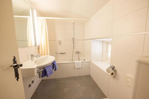 a white bathroom with a sink and a bath tub at Hotel Chesa Spuondas in St. Moritz
