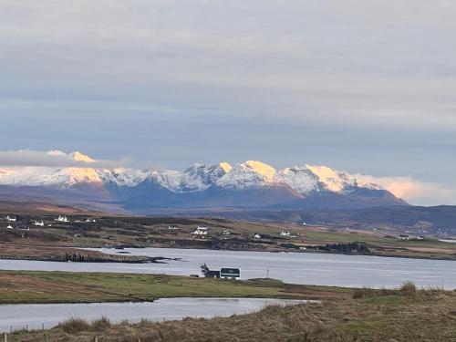 a large body of water with snow capped mountains in the background at BluePigeons Pods Roag Dunvegan in Lonmore