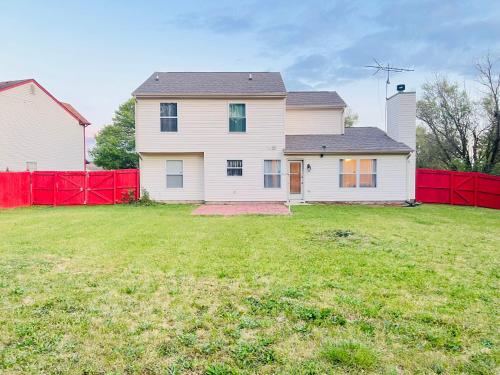 a white house with a red fence in a yard at Find your home away from home in our delightful 4 bedroom space in Indianapolis