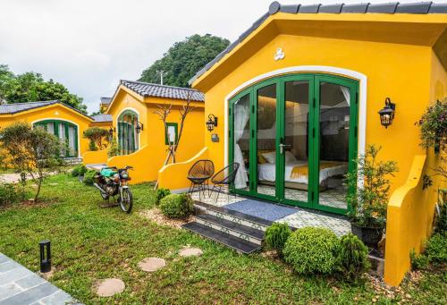 a yellow house with a bed in a yard at Plum Village Moc Chau in Mộc Châu