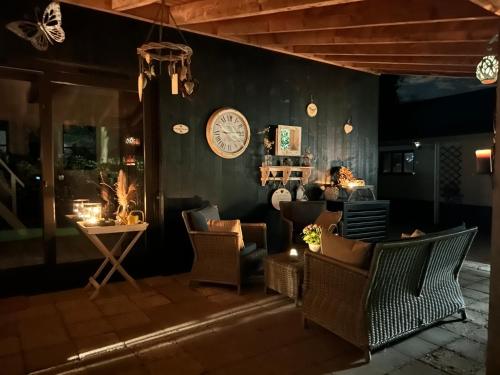 a living room with chairs and a clock on the wall at Heikant Hoeve met Jacuzzi in Baarle-Nassau