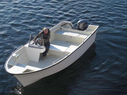 a man standing in a boat in the water at Hareid in Hareid