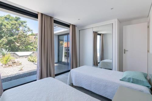 Un dormitorio con dos camas y una gran ventana. en CasaMar, en Jardim do Mar