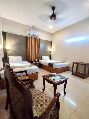 a hotel room with two beds and a table at Star Guest House in Karachi