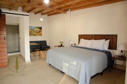a bedroom with a large white bed and a couch at Casa Ciprés in Valle de Guadalupe