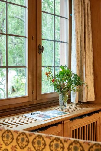 a vase of flowers sitting on a counter next to a window at Hotel Chesa Spuondas in St. Moritz