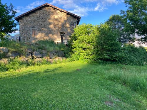 un vieux bâtiment en pierre dans un champ herbeux avec un arbre dans l'établissement Relais nofeer, à Monlet