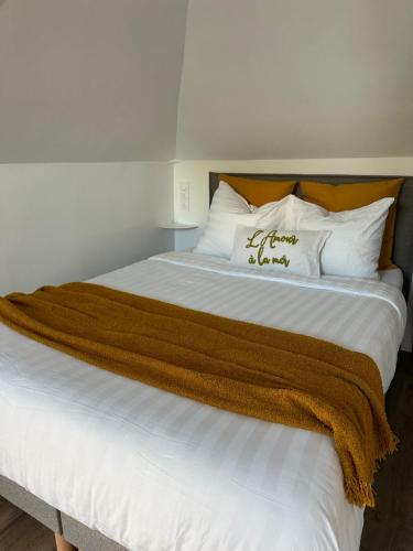 Elle comprend un grand lit blanc avec une couverture brune. dans l'établissement L'Amour à la mer, à Honfleur