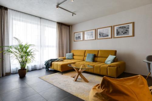 a living room with a yellow couch and a table at Apartmán Leonardo - city center in Trnava
