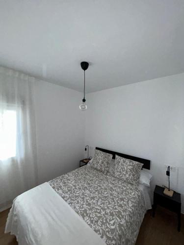 a white bedroom with a bed and a window at La Casita de Josefa in Zahara de la Sierra