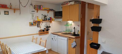 une petite cuisine avec une table et une petite cuisine avec un comptoir dans l'établissement Studio calme pour 4 ou 6 personnes, skis aux pieds, aux Menuires