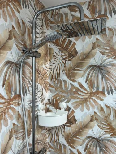 a shower in a bathroom with a mural of tropical leaves at La Casita de Josefa in Zahara de la Sierra
