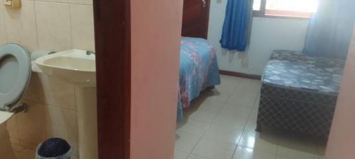 a bathroom with a sink and a toilet and a bed at Hospedaria Meu lar in Rio das Ostras