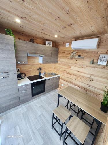 - une cuisine avec des murs en bois, une table et un évier dans l'établissement Le Cozy Cottage - Chalet avec parking, à Châtillon-sur-Cher