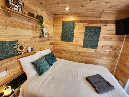 une chambre avec un lit dans une pièce aux murs en bois dans l'établissement Le Cozy Cottage - Chalet avec parking, à Châtillon-sur-Cher