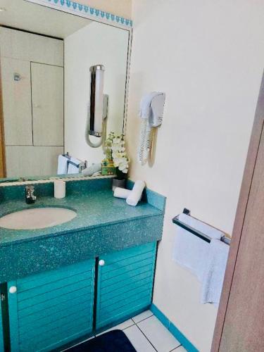 Un baño con un lavabo azul y un espejo. en Marina-Carayou 2, en Les Trois-Îlets