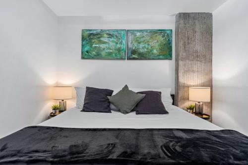 a bedroom with a large bed with three paintings on the wall at Best views! Lux 9th fl Gym Pking Pool Htub King BD in Salt Lake City